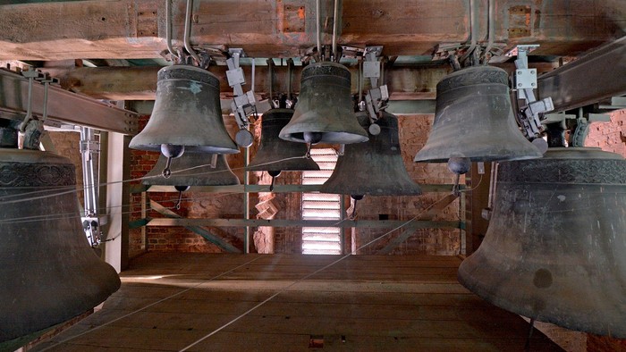 Mehrere Glocken hängen in einem Turm.