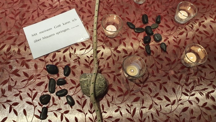 Tisch mit Kerzen und Steinen, Schild auf Deutsch