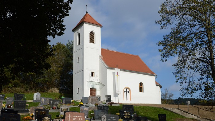 Weiße Kirche mit rotem Dach und Friedhof davor