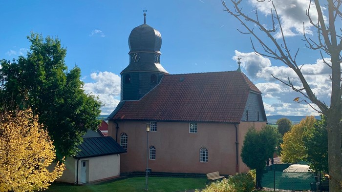 Kirchengrundstück mit grünem Rasen und Bäumen unter blauem Himmel