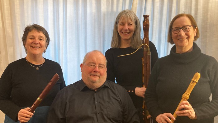 Vier Personen posieren mit Musikinstrumenten.
