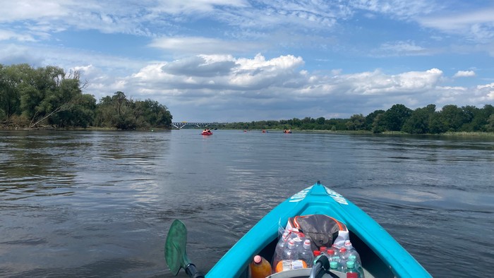 Die vordere Spitze eines Paddelbootes auf der Oder, im Hintergrund sieht man die Eisenbahnbrücke über die Oder zwischen Frankfurt und Slubice.