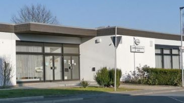 Modernes Bürogebäude mit großen Fenstern und Beschilderung.