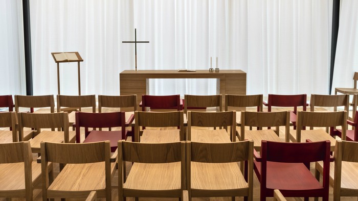 En kirke med træstoler og alter foran et hvidt tæppe.