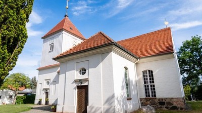 Weißes Kirchengebäude mit rotem Dach und Turm unter blauem Himmel