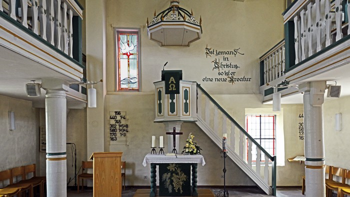 Kleines Kircheninnere mit Altar, Kirchenbänken und Empore