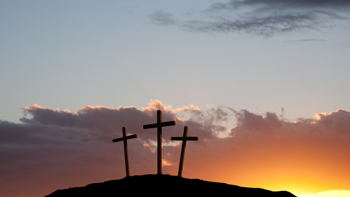 Drei Kreuze auf einem Hügel bei Sonnenuntergang