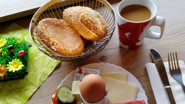 Frühstück mit Brötchen, Kaffee, Ei, Wurst und Gemüse