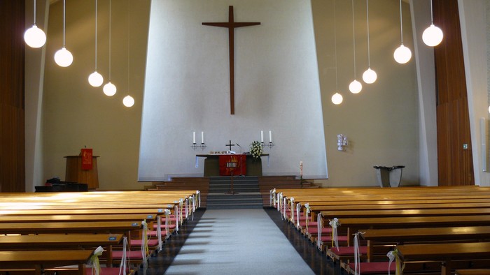 Leere Kirche mit Holzbänken und Kreuz