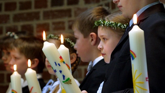 Kinder, die in einer Reihe brennende Kerzen halten