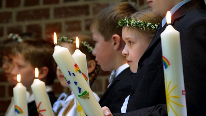 Kinder, die in einer Reihe brennende Kerzen halten
