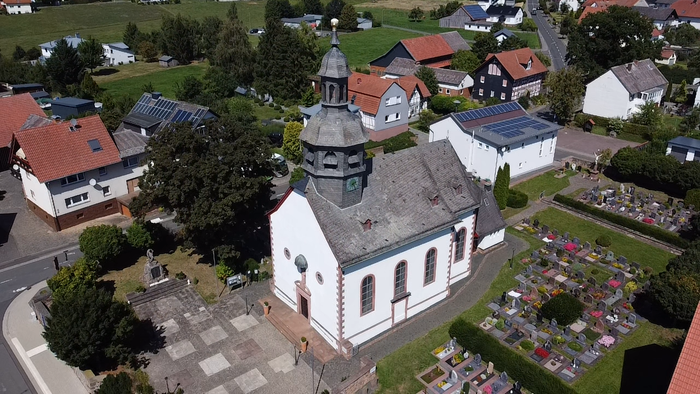 Überblick einer Kirche mit umliegendem Friedhof und Häusern