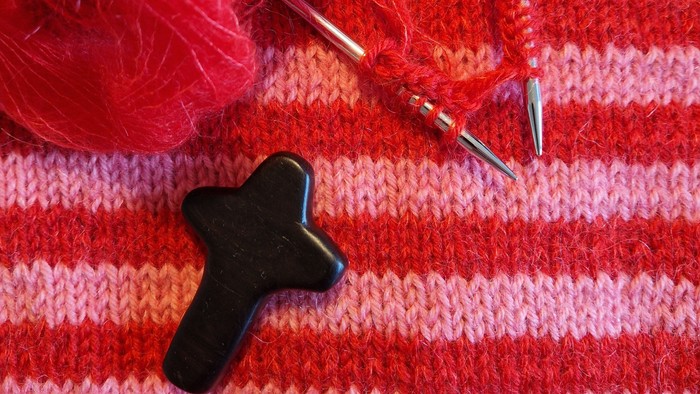 En håndklæde i røde og orange striber med en svart korset knap og strå.