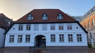 Weißes Gebäude mit rotem Dach und vielen Fenstern
