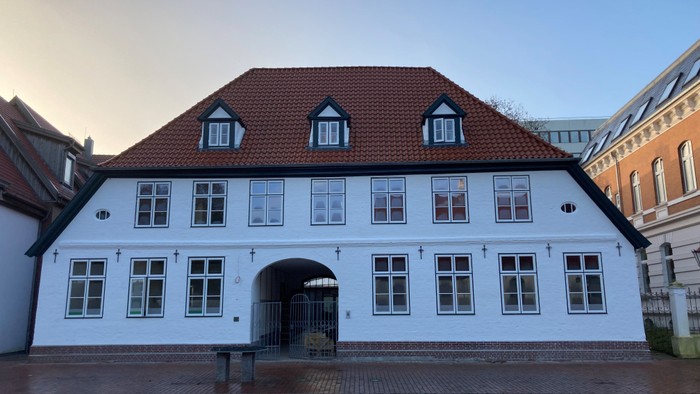 Weißes Gebäude mit rotem Dach und vielen Fenstern