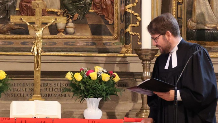 Zwei Priester stehen vor einem Altar mit Blumen und Kerzen.