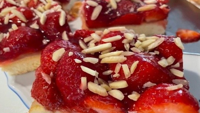 Köstliche Erdbeerbiskuitkuchen, belegt mit gehackten Nüssen und frischer Erdbeerglasur.