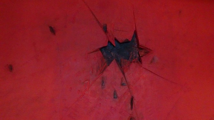 Nahaufnahme eines Spinnennetzes auf einer tiefroten, strukturierten Oberfläche mit einer Spinne in der Mitte.