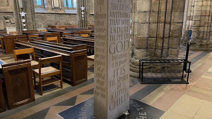A solemn church interior with a memorial plaque inscribed with a touching spiritual message.