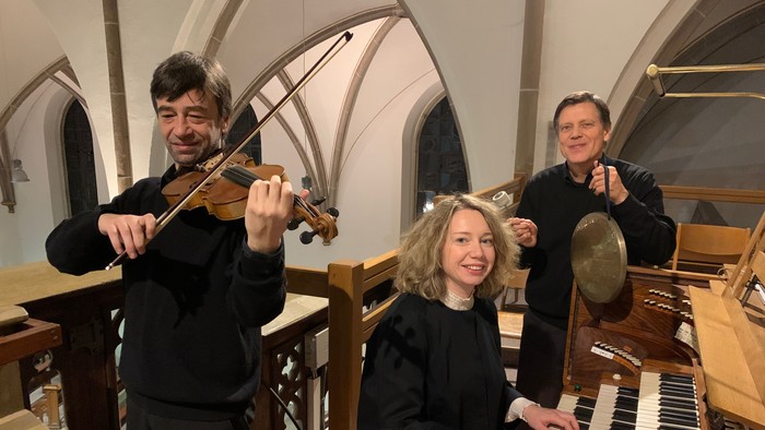 Musiker, die Geige, Orgel und Schlagzeug in einer prächtigen Kirche spielen.