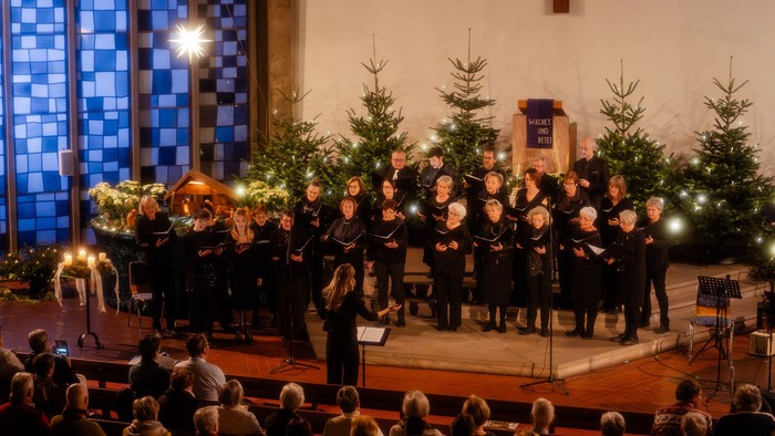 Kirchenchor tritt auf der Bühne mit Weihnachtsdekoration auf.