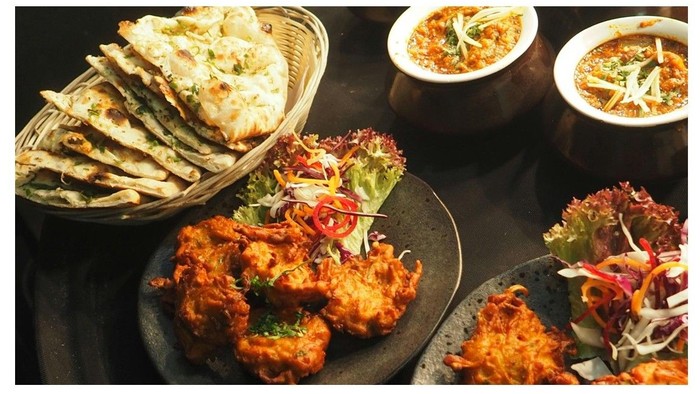 Farverigt asiatisk-inspireret måltid med sprøde stegte snacks, frisk salat og skåle med aromatiske supper fyldt med urter.