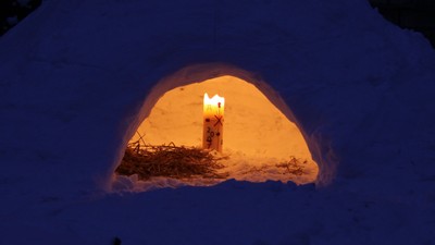 Eine kleine Schneehöhle mit warmer Beleuchtung im Schnee.