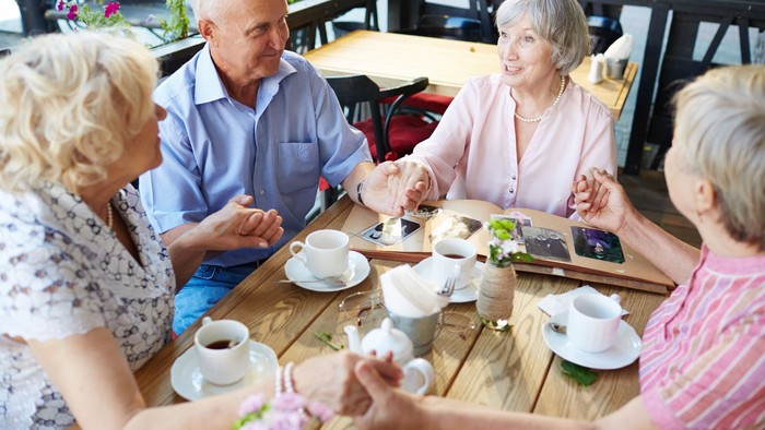 Eine Gruppe älterer Menschen sitzt an einem Tisch und trinkt Tee.