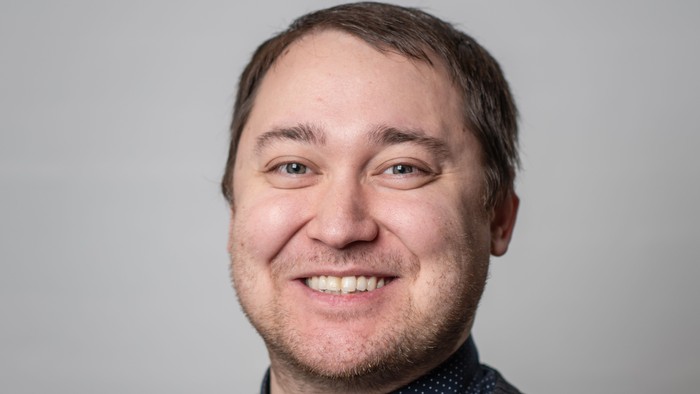 En smilende mand med kort hår og stribet trøje.