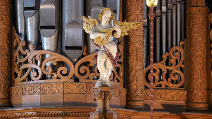 Engelstatue vor einem Holzorgelpfeiler