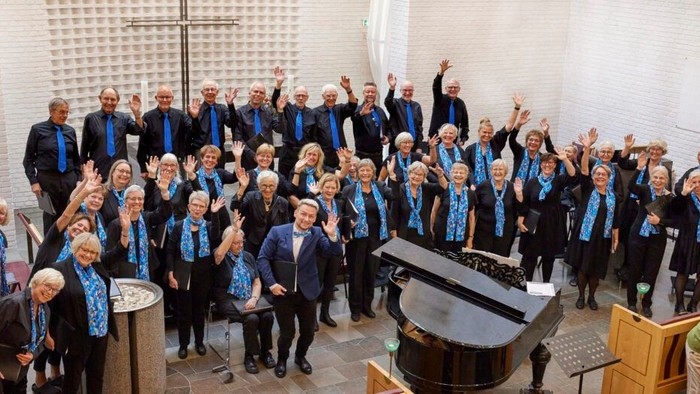 Et glad kor løfter hænderne glædestrålende under en optræden i en kirke.