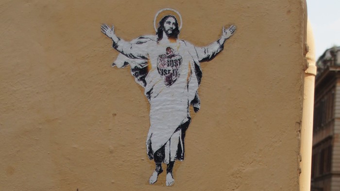 Ein Bild einer Person an einer gelben Wand über Kopfsteinpflaster.