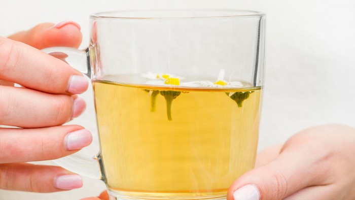 Frau hält Glas mit Teeblättern in der Hand
