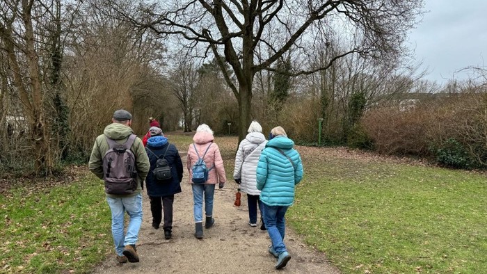 Menschen gehen in einer kleinen Gruppe auf einem Feldweg