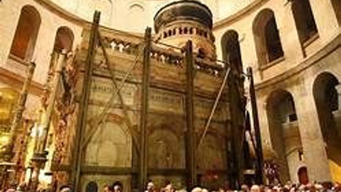 Large group of people inside a historic building with arches and columns.