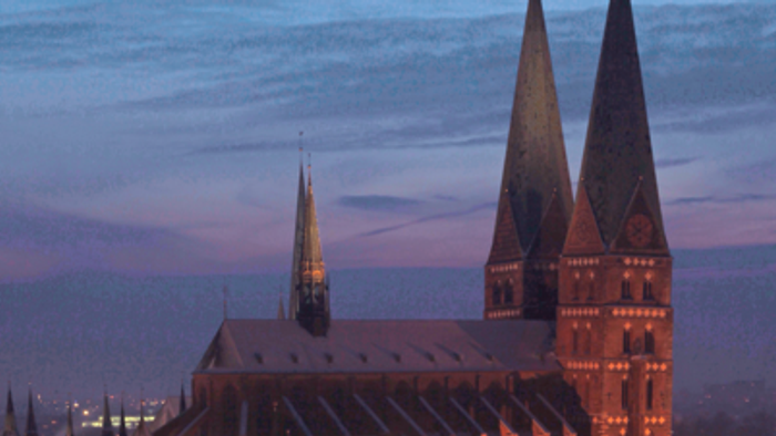 Großes, beleuchtetes Kirchengebäude bei Dämmerung in Schneelandschaft