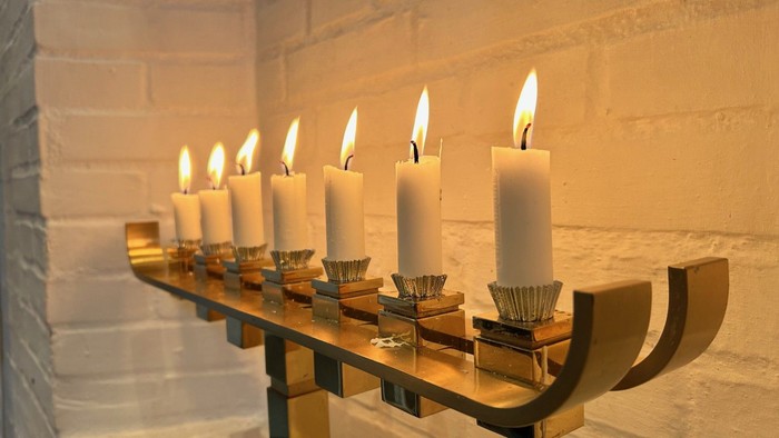 Lys tændt i en træholder foran en murstensvæg