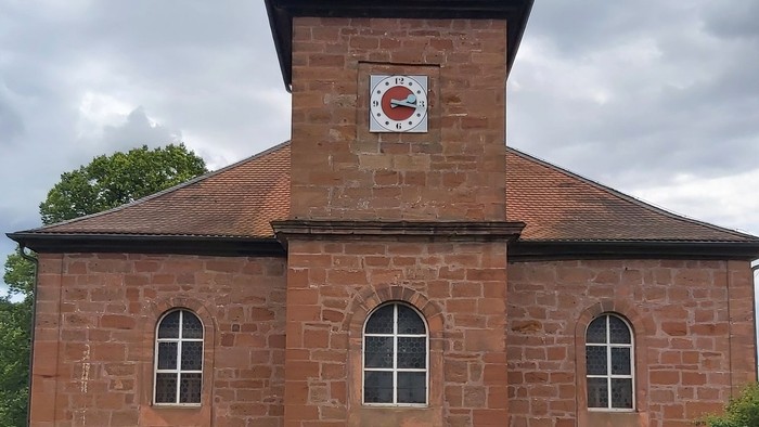 Rotes Backsteingebäude mit einem Turm und Rundbogenfenstern.