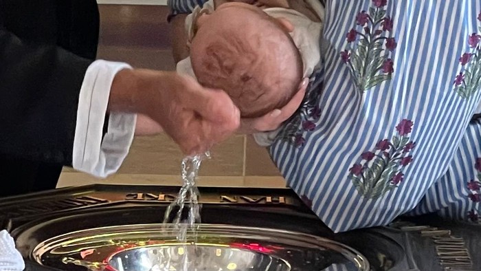 Barnedåb hvor præst fører vand til dåbsbarnets hoved 