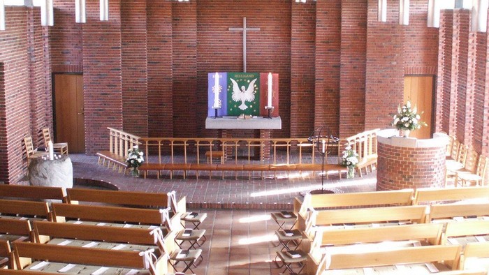 Indre del af kirke med træbænke og alter.