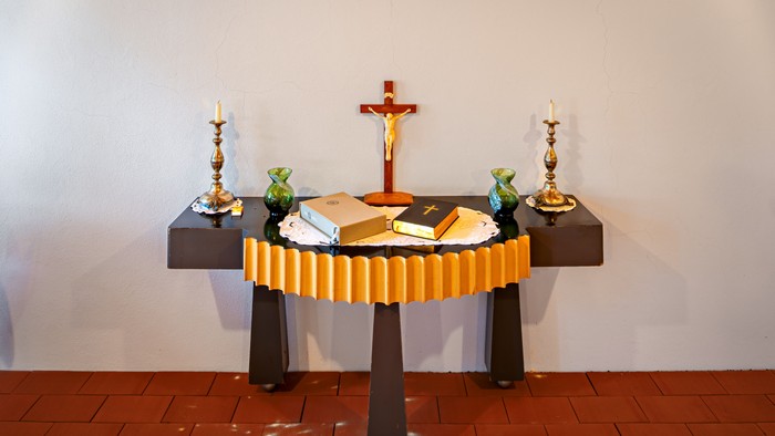 Altar mit Kreuz, Kerzen und Büchern
