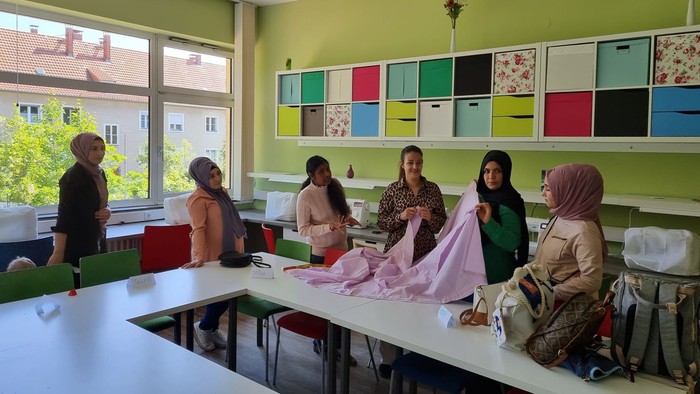 Ein Gruppenfoto von Frauen in einem Raum mit bunten Regalen und Fenstern.