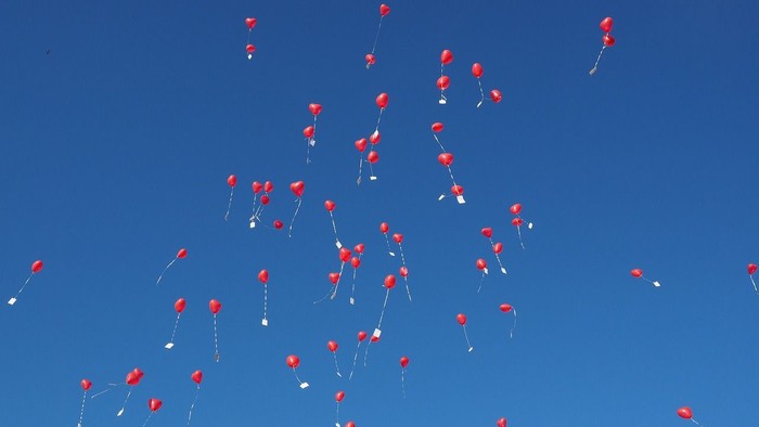 Viele rote Ballons schweben am klaren blauen Himmel.