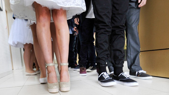 En brud og to mænd står tæt på hinanden, deres ben og sko er synlige.