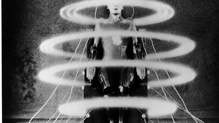 A person sits in a chair with lights creating circular patterns around them.