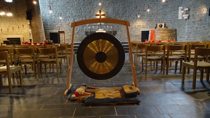 Im Raum steht eine große Trommel auf einem Ständer, umgeben von Tischen und Stühlen.