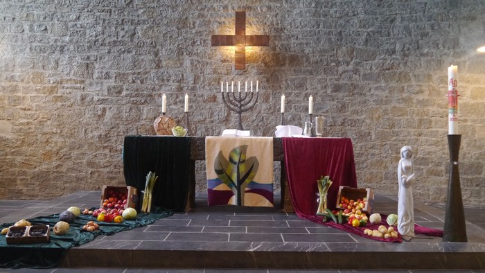 Ein Altar mit Kerzen, Obst und Gemüse vor einer Steinwand