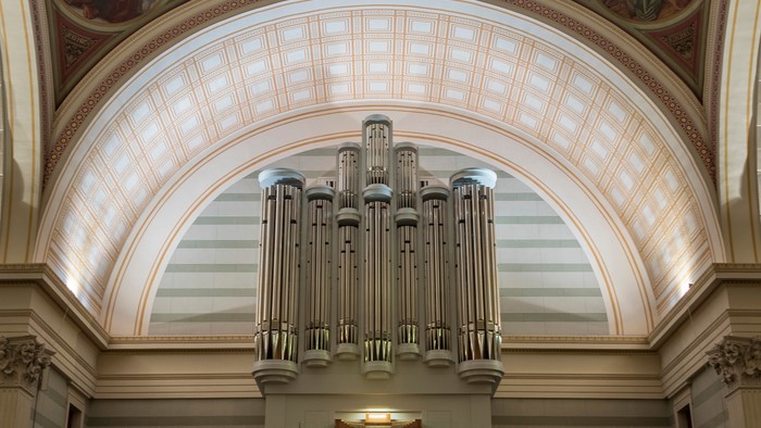 Große Kirchenorgel unter einem gewölbten Deckenfenster