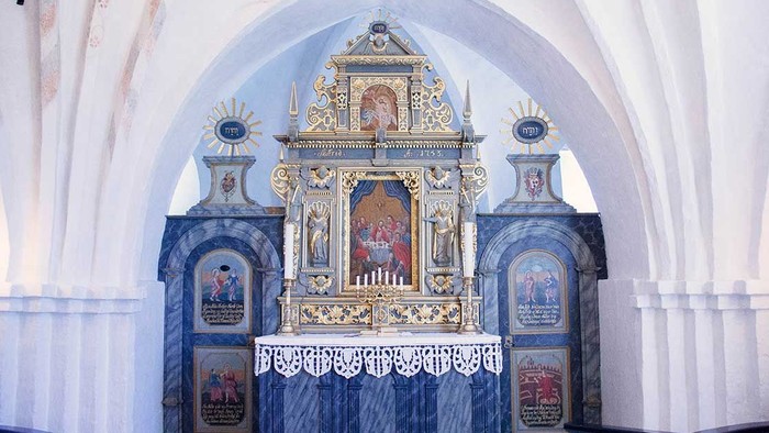 En prægtig altertavle i en kirke med detaljerede malerier og gulddekor.