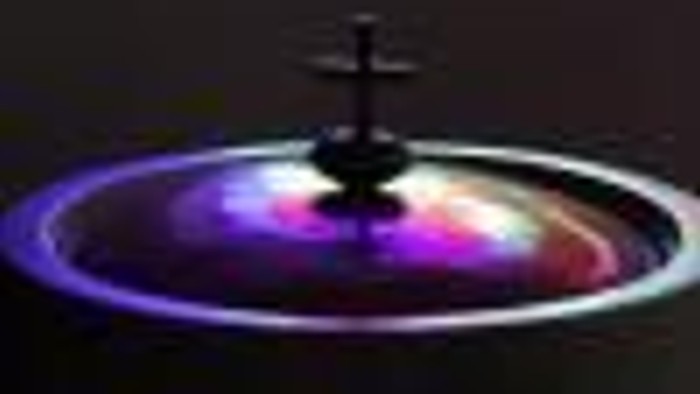 Das Bild zeigt eine farbenfrohe Lichtinstallation mit einem kleinen Objekt in der Mitte.